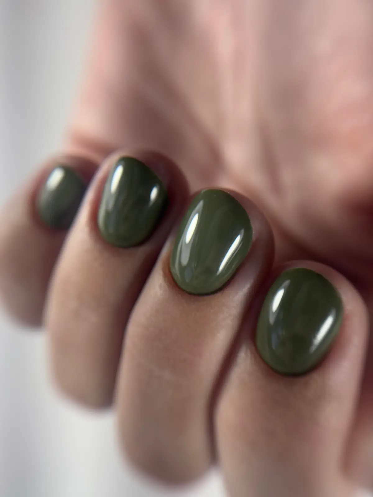 Unhas curtas e arredondadas em gel verde-oliva.