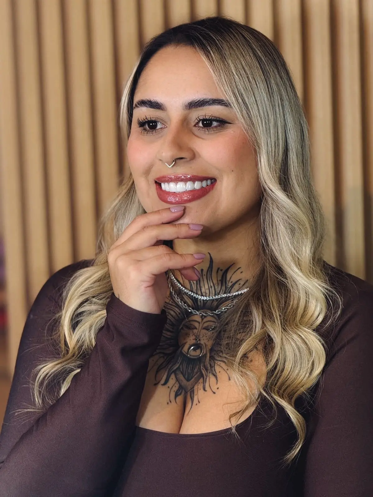 Retrato de Raiane, instrutora, sorrindo com a mão apoiada no queixo.